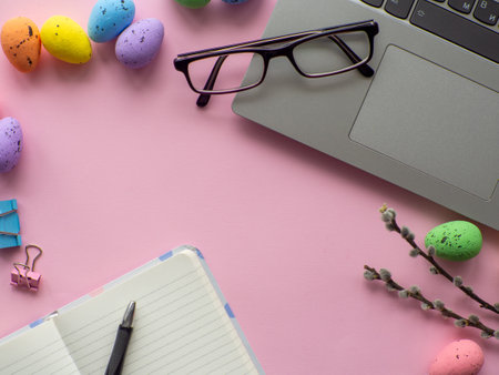 Easter work concept. Flat lay. Business work desk with devices and happy easter holiday multicolored...