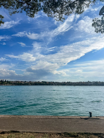 Water landscape of lago di Garda in the province of Verona in Veneto. Coast of the largest in Italy Garda lake. Stunning view over the Garda lake, seen from Peschiera del Garda. Beautiful summer day.の写真素材