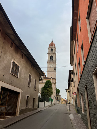 Pontevico, Italy. Deserted street in an italian town with old houses. Summer travel in Italy. Bell tower of church of Saints Thomas and Andrew the Apostlesの写真素材