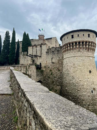 The stone castle features a rectangular shape with a round tower at one corner topped by a conical...