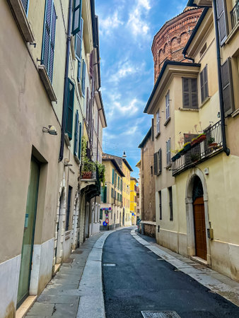 View of a narrow empty alleyway with facades of old buildings. Traditional buildings with balconies, shutter windows and colored walls in typical italian street in Brescia.の写真素材