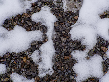 A close up of a rocky, snow covered ground. The snow is covering the ground and the rocks are scattered throughout.の写真素材