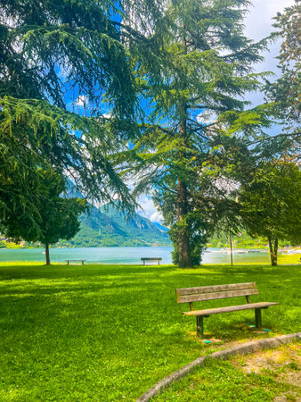 Crone public park with empty benches on Lake Idro, Lombardy, Italy. Empty lakefront with beach of the small Crone village. Tourist resort in Brescia province, Lombardy.の写真素材