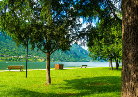 Crone public park with empty benches on Lake Idro, Lombardy, Italy. Empty lakefront with beach of the small Crone village. Tourist resort in Brescia province, Lombardy.の写真素材