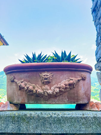 A beautifully crafted terracotta garden planter set against a rustic stone wall. This image captures the charm of outdoor decor, ideal for garden enthusiasts.の写真素材