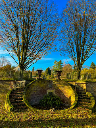 A stunning display of vintage bronze vases elegantly positioned on a circular platform in a serene park setting. The clear blue sky enhances the beauty of this picturesque scene.の写真素材