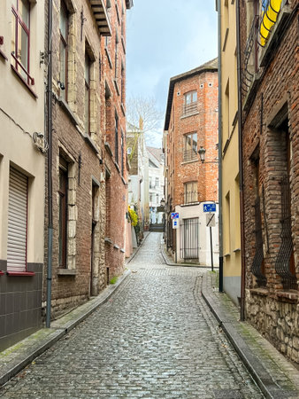This captivating photograph showcases an empty street in Brussels, Belgium, featuring beautiful brown brick buildings lining a picturesque cobblestone road, evoking a serene atmosphere.の写真素材