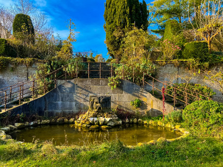 wide-angle view captures a serene garden featuring a tranquil pond surrounded by beautifully arranged rockery and vibrant lush greenery, ideal for relaxation and nature appreciation. Waterloo, Belgiumの写真素材
