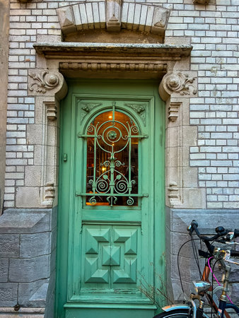 A vibrant green door adorned with intricate designs stands out beautifully against the rough texture of a historic brick building, showcasing the charm of architectural details.の写真素材