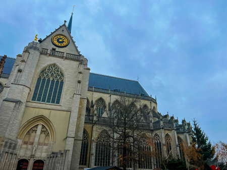 A breathtaking view of Leuven cathedral featuring an intricate clock tower against a backdrop of a clear blue sky adorned with fluffy white clouds, showcasing architectural beauty.の写真素材