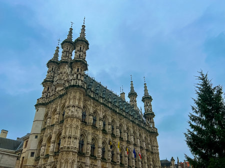 The stunning gothic architecture of leuven town hall stands majestically under a dramatic cloudy sky, adorned with festive christmas decorations, creating a captivating holiday atmosphere.の写真素材