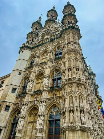 The stunning gothic architecture of leuven town hall stands majestically under a dramatic cloudy sky, adorned with festive christmas decorations, creating a captivating holiday atmosphere.の写真素材