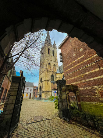 This captivating wide-angle photo showcases a tall church tower as viewed from the entrance gate of an old brick building, highlighting the architectural beauty and historical charm of the scene.の写真素材