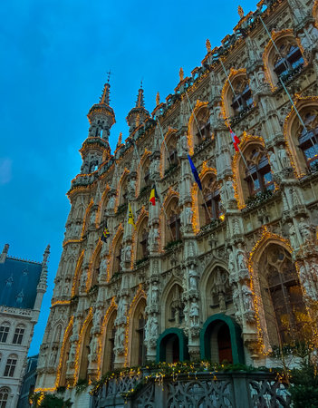 This captivating cityscape of Leuven, Belgium showcases blend of historical architecture adorned with vibrant flags and banners. The town hall of Leuven at night, with Christmas lights and decorationsの写真素材