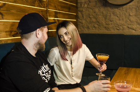 Happy beautiful couple in love sitting in bar with drinks and having funの写真素材