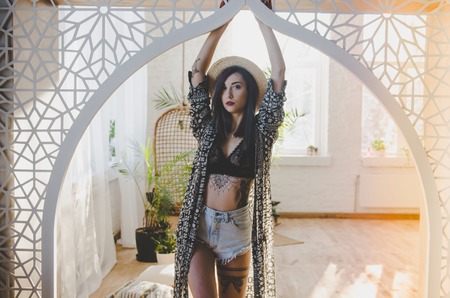 Young beautiful model posing in casual clothes, wearing straw hat, in studioの写真素材