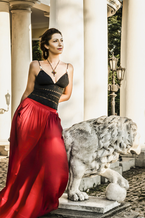 Woman in red beautiful fashioned dress in city near beautiful architecture.の写真素材