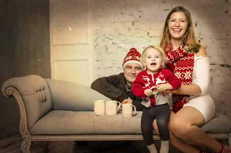 Happy family of mother father and baby sitting together on sofa and smiling, playing together.の写真素材