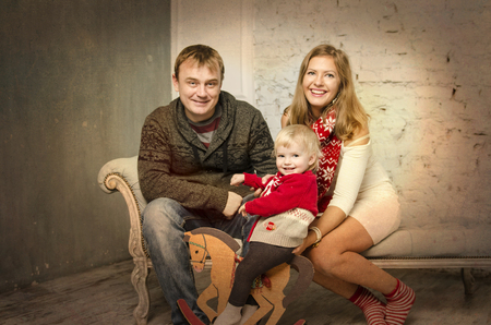Happy family of mother father and baby sitting together on sofa and smiling, playing together.の写真素材