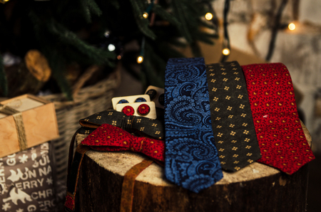 Set of beautiful men accessories of bow tie, neck tie, cufflinks, man's scarf with present box on christmas tree backgroundの写真素材