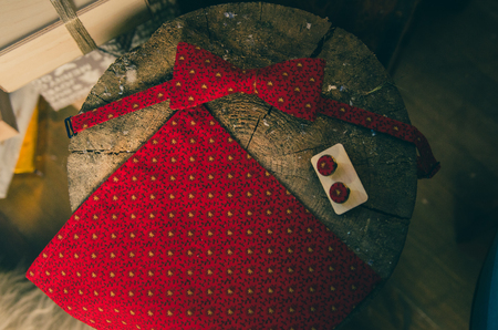 Beautiful red polka dot bow tie and cufflinks on wooden present boxの写真素材