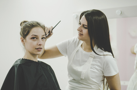 Beautiful young professional woman tweezing shirtless woman eyebrows Mikrobleyding eyebrows workflow in a beauty salonの写真素材