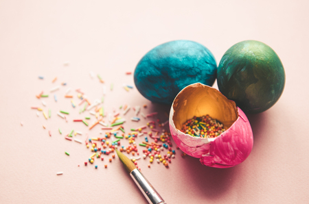 Beautiful colorful easter eggs with confectionery sprinkling and brush on pink backgroundの写真素材