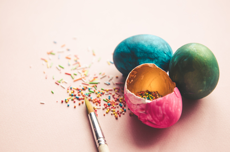 Beautiful colorful easter eggs with confectionery sprinkling and brush on pink backgroundの写真素材