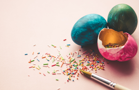 Beautiful colorful easter eggs with confectionery sprinkling and brush on pink backgroundの写真素材