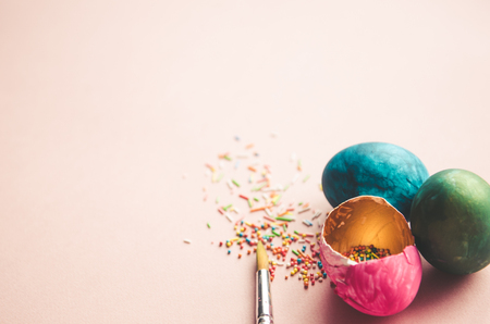 Beautiful colorful easter eggs with confectionery sprinkling and brush on pink backgroundの写真素材