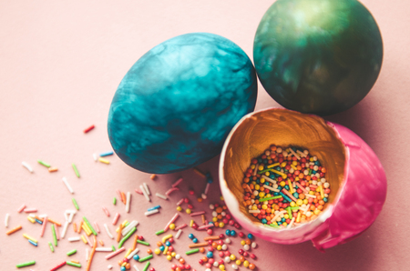 Beautiful colorful easter eggs with confectionery sprinkling and brush on pink backgroundの写真素材
