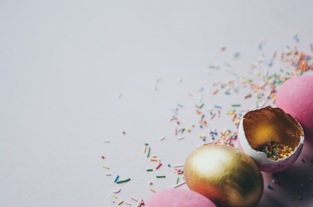 Beautiful colorful pink and golden easter eggs with confectionery sprinkling and brush on pink backgroundの写真素材