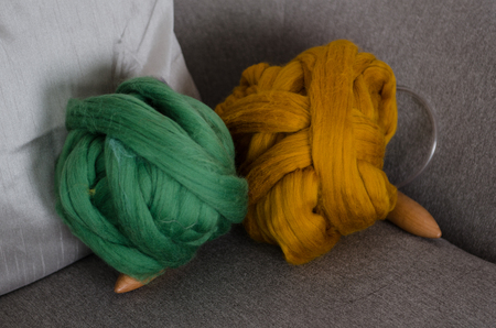 colorful Green and brown merino wool on grey arm chair with needlesの写真素材