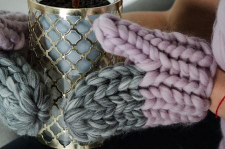 beautiful merino wool knited gloves holding vase, close upの写真素材