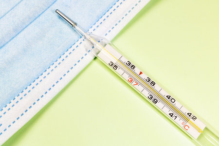 Mercury thermometer with medical cloth on table with green background.
