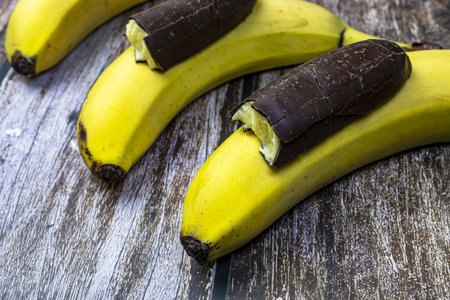 Bananas in chocolate on a wooden table.の写真素材