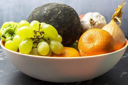 Mix of fresh fruits and vegetables in a bowl on the table.の写真素材