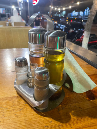 Condiment Set on Wooden Table in Outdoor Restaurant at Night Urban Dining Atmosphereの写真素材