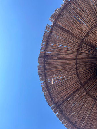 Straw Beach Umbrella Against Clear Blue Sky Summer Vacation Conceptの写真素材