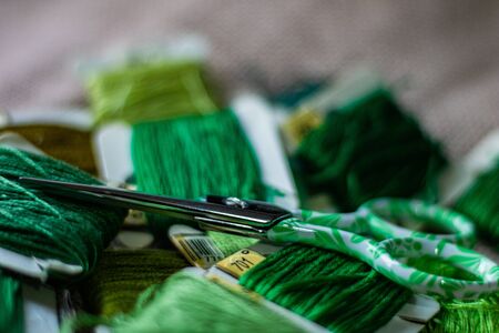 Collection of green colors of yarns with a green scissors on a clothの写真素材
