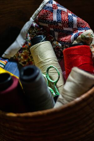 Various colors of thread rolls sits in wooden basket