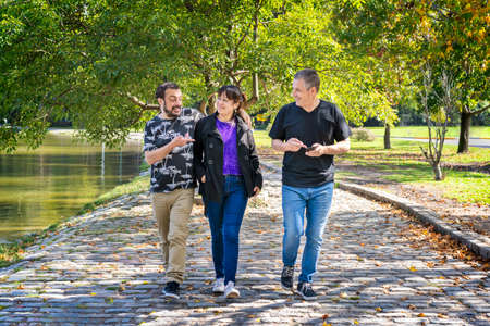 Group of friends walking in a park chatting, laughing and having a good timeの写真素材