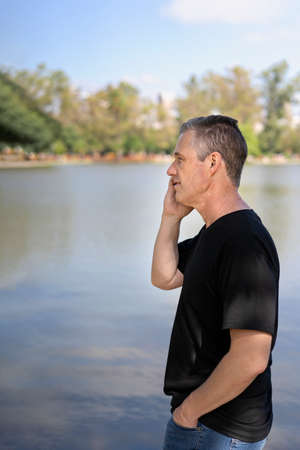 Mature businessman talking on cell phone at a lake