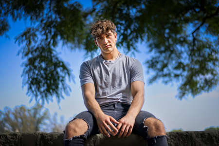 Confident young blonde man portrait, summer trees background. copy-spaceの写真素材