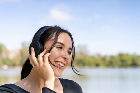Young woman listening to music outdoors with headphones. Expression of happiness, winning attitude. copy-spaceの写真素材