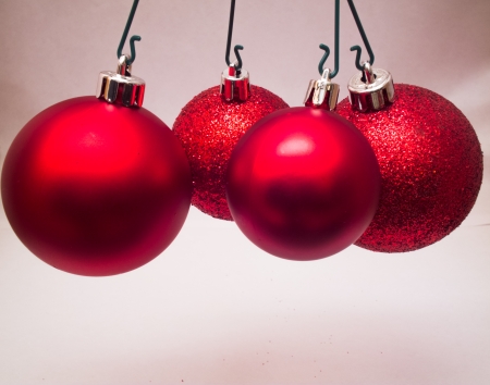 four red christmas balls pendin on white backgroundの写真素材