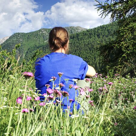 girl sitting on the grass in the mountainsの写真素材
