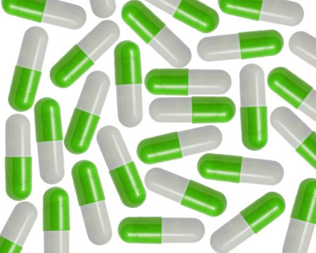 Green and White Capsules splattered over a white background.の写真素材