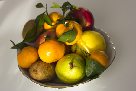 plate with winter fruit, tangerines, apples, pomegranates on a light backgroundの写真素材