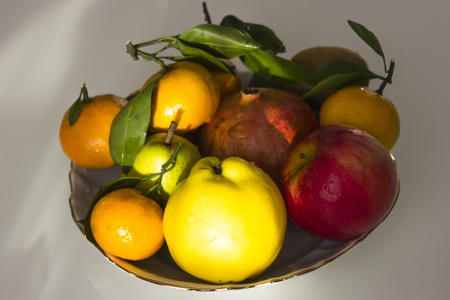 plate with winter fruit, tangerines, apples, pomegranates on a light backgroundの写真素材